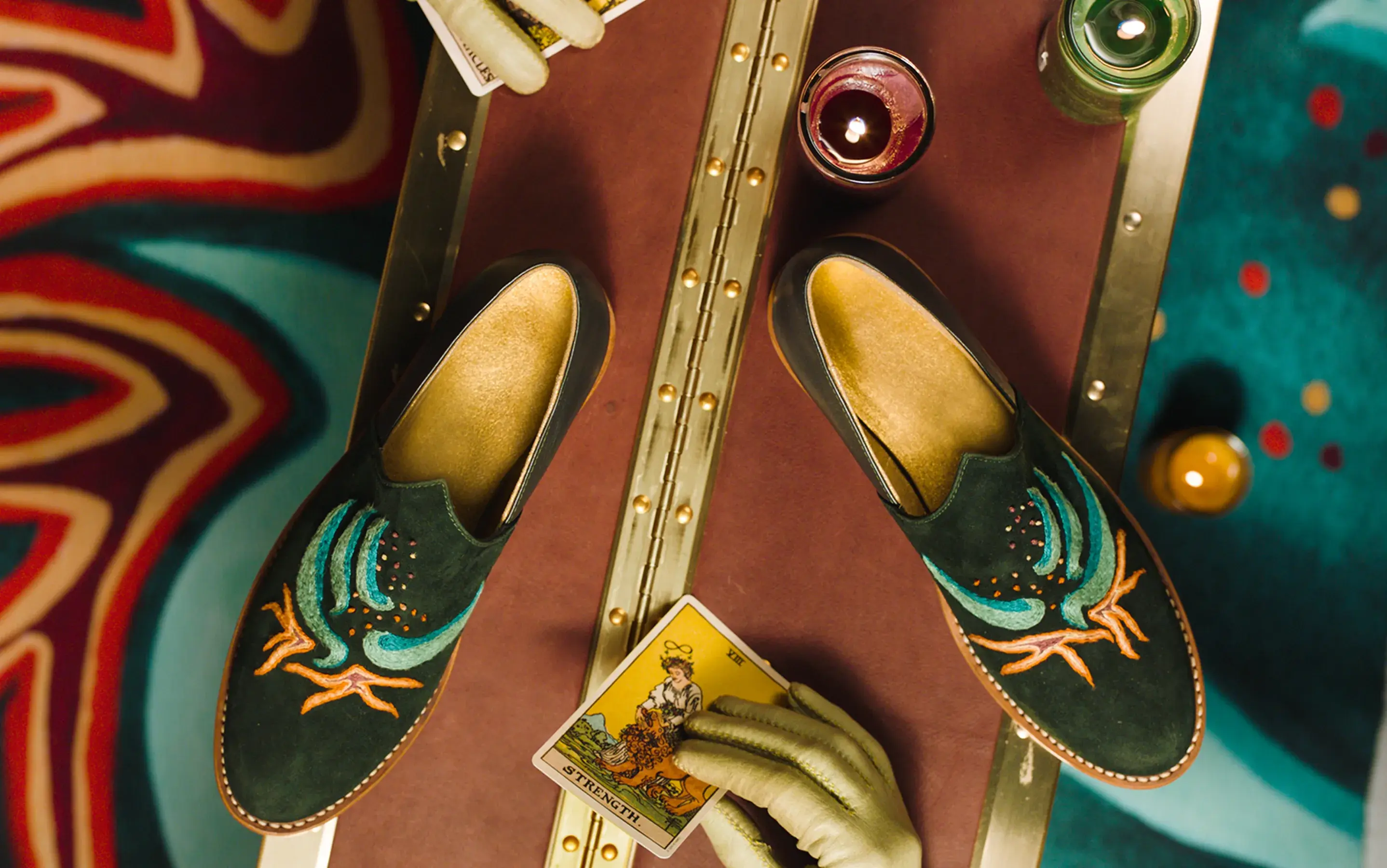 Bathke Bespoke: overhead shot of embroidered suede loafers styled with candles and a tarot card