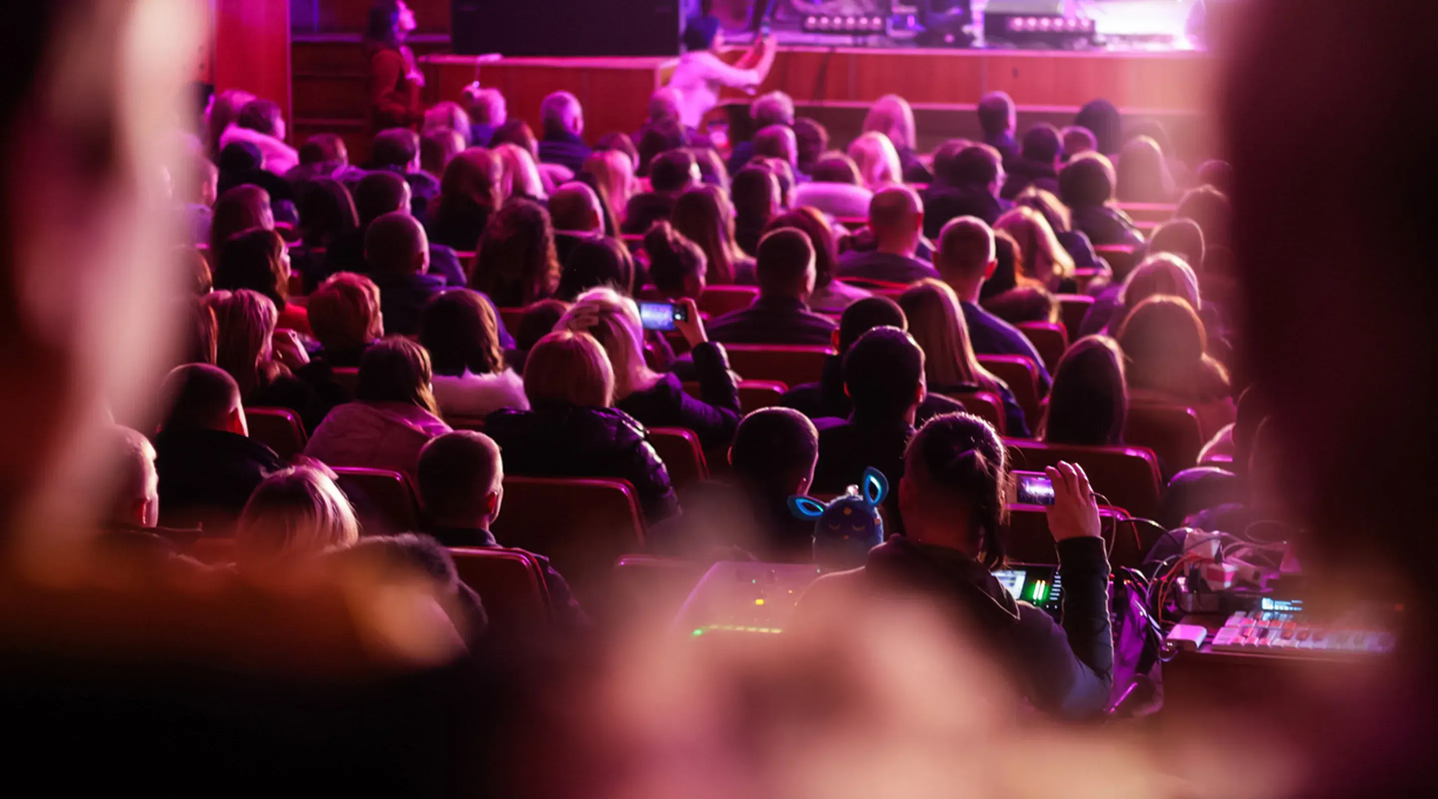 Audience in a theater washed in magenta light