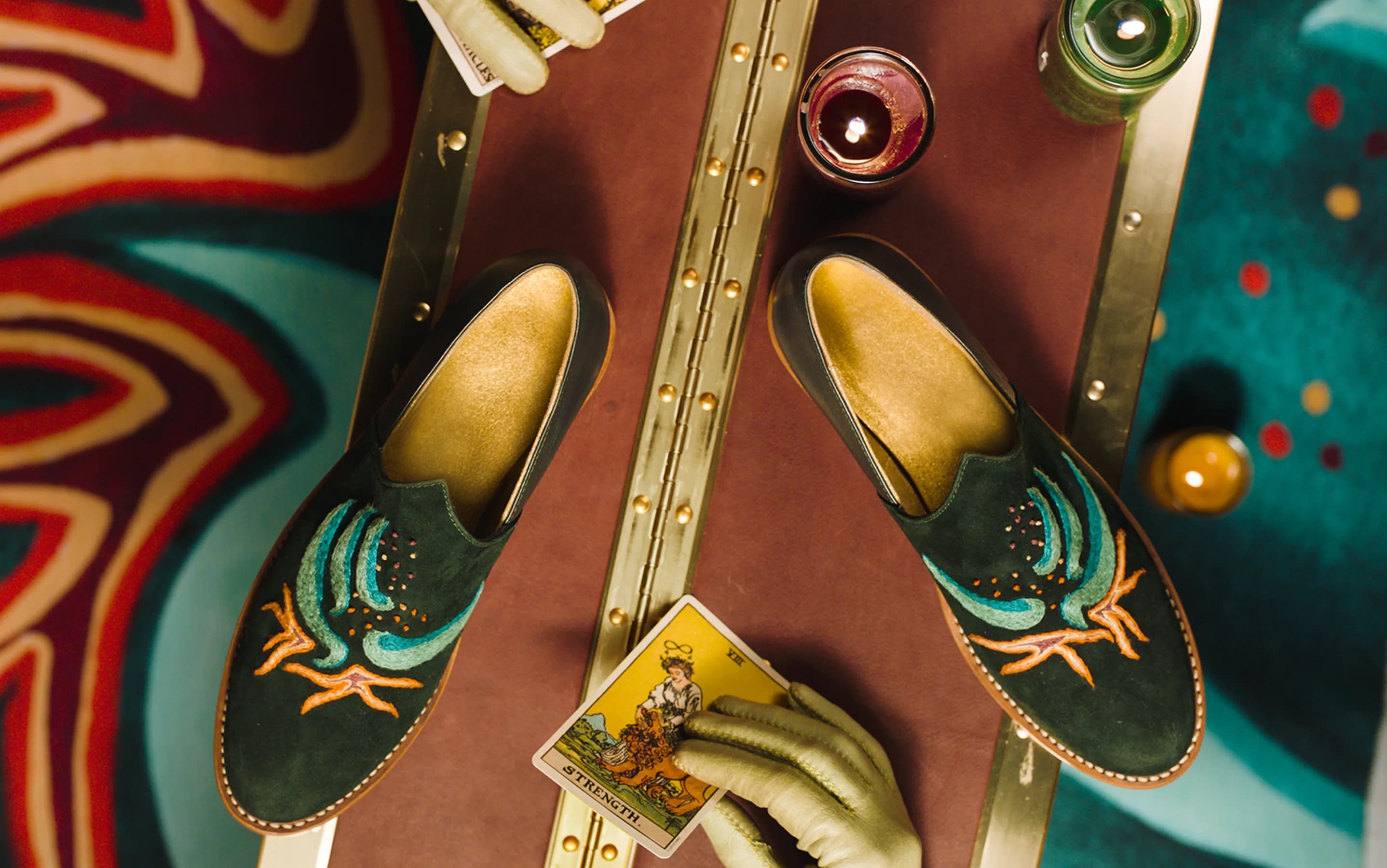 Bathke Bespoke: overhead shot of embroidered suede loafers styled with candles and a tarot card