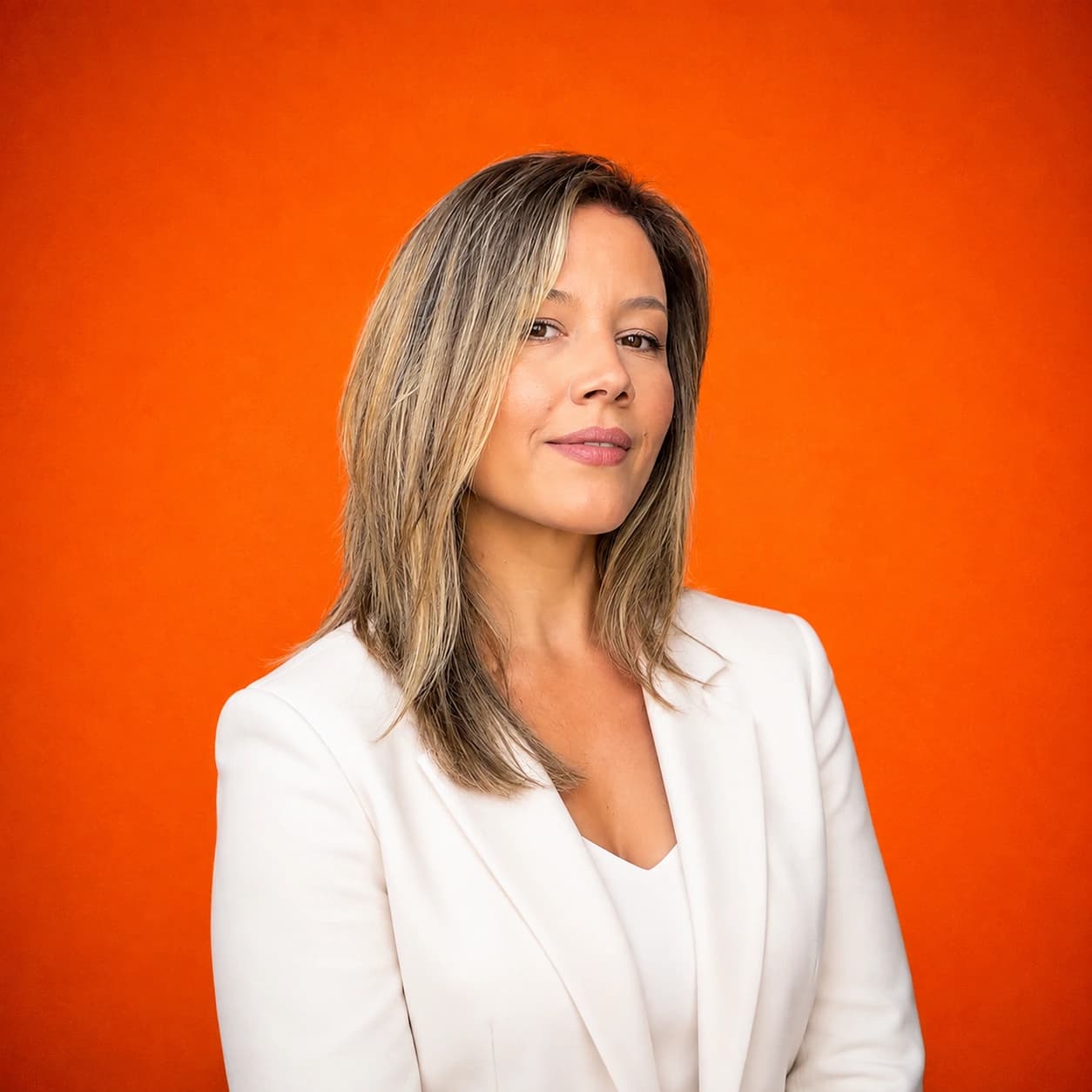 Portrait of Andjela Stojanović, creative director of The Shadow Legacy, in a cream blazer against an orange backdrop